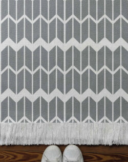 Alfombra tejida geométrica estilo chevron en tono gris.