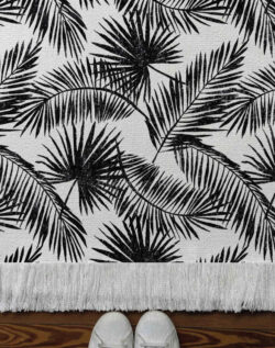Alfombra tejida diseño botánico de distintos tipos de hojas tipo palmera en color negro.