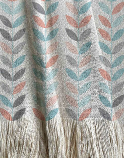 Manta tejida estilo enredadera, hojas de distintos colores en tonos aqua, gris y coral.