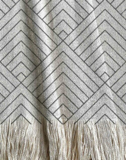 Manta tejida con diseño geométrico, triángulos tipo montañas en tonos grises.