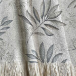 Manta tejida diseño botánico, hojas y ramas pintadas en acuarela. Tonalidades grises y visones.