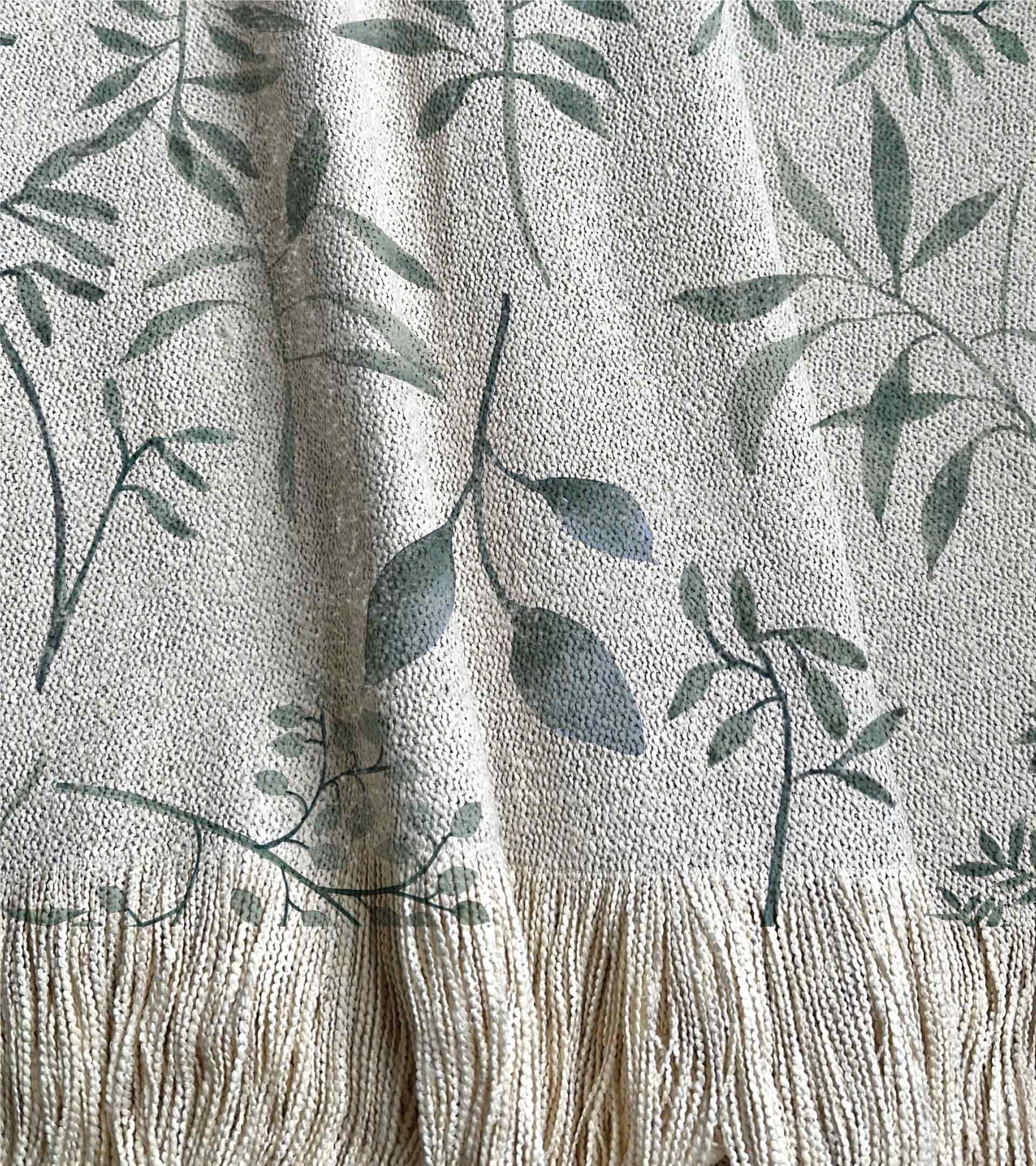 Manta tejida, con un diseño botanico con hojas y ramas de color verde y azul