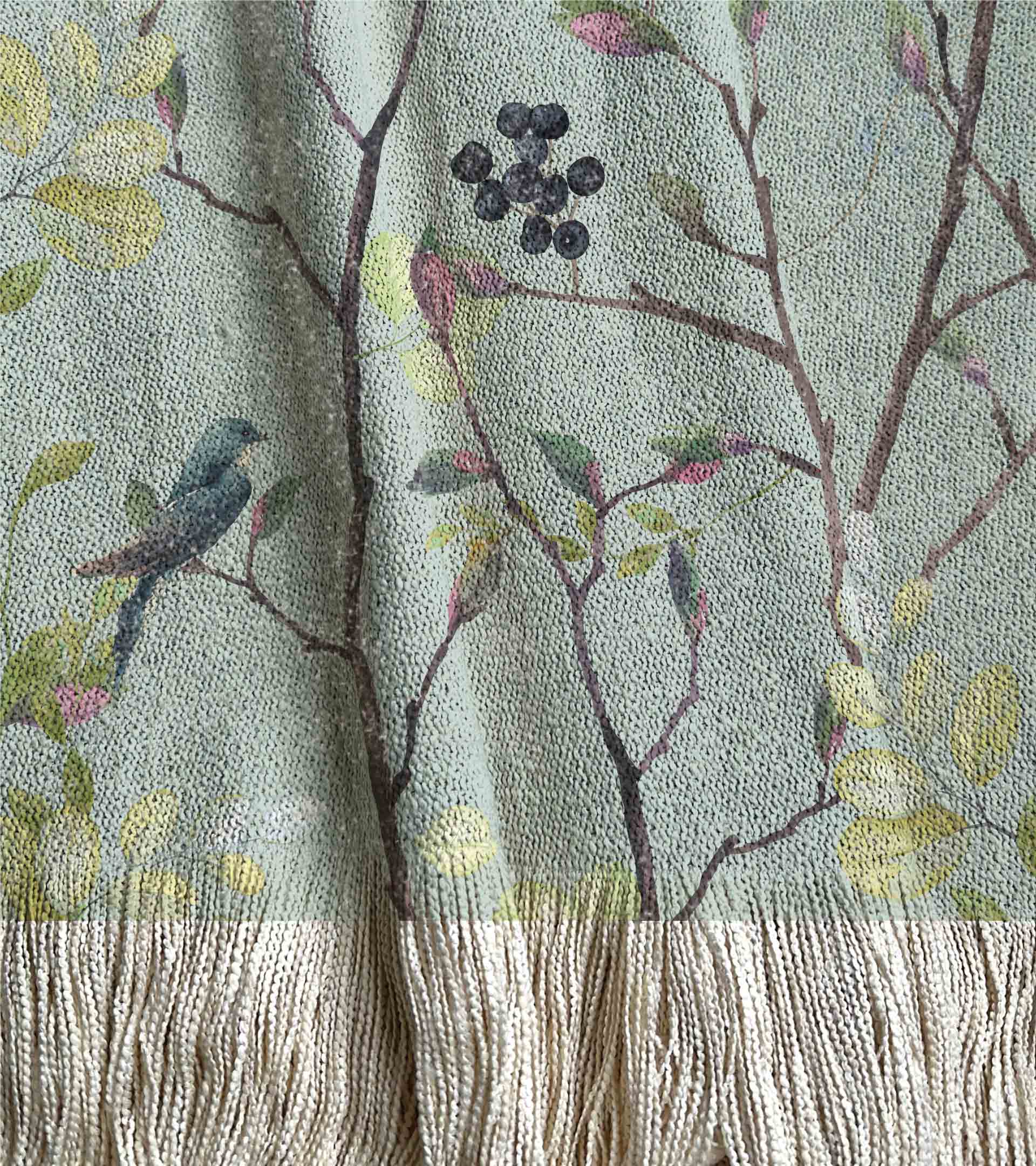 Manta tejida con un diseño botanico, con pájaros y flores. Color turquesa, frutos azules y hojas verdes