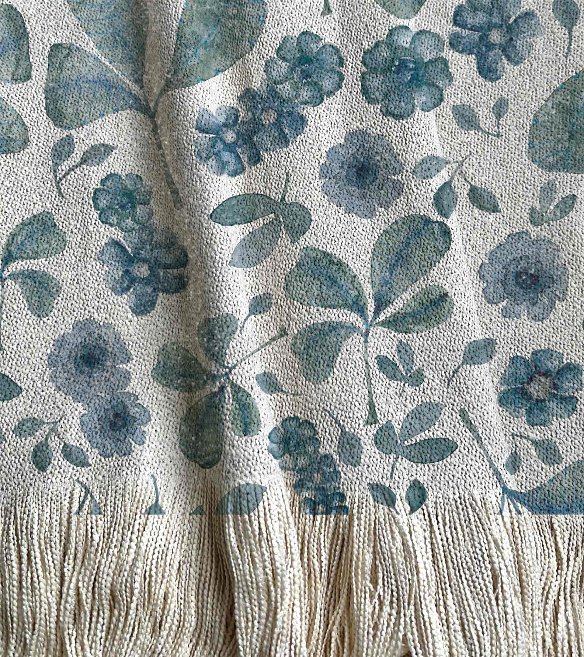 Manta tejida con diseño botanico, hojas verdes y flores grandes azules