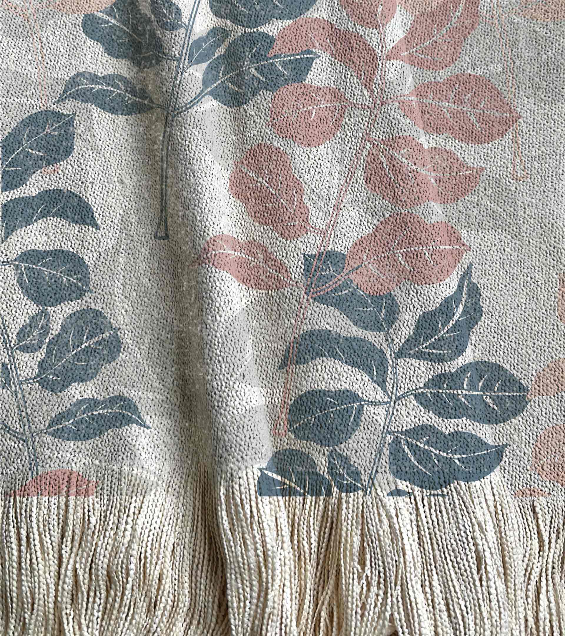Manta tejida diseño botanico con ramas y hojas de color rosado, azul y gris